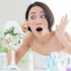 顔のシミをみて驚く女性
