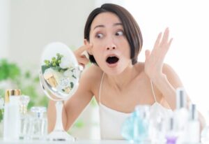 顔のシミをみて驚く女性