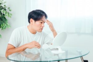 鏡を見て悩む男性